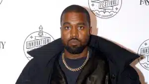 A man wearing a dark jacket and gold chain, standing in front of a backdrop with "INNOVATION FESTIVAL" and "FAST COMPANY" printed on it.