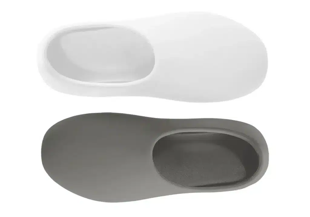 Pair of slip-on shoes, one white and one gray, with rounded edges and a minimalist design.