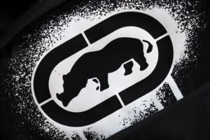 A black and white image showing the silhouette of a rhinoceros inside an oval shape, with a speckled texture surrounding it.