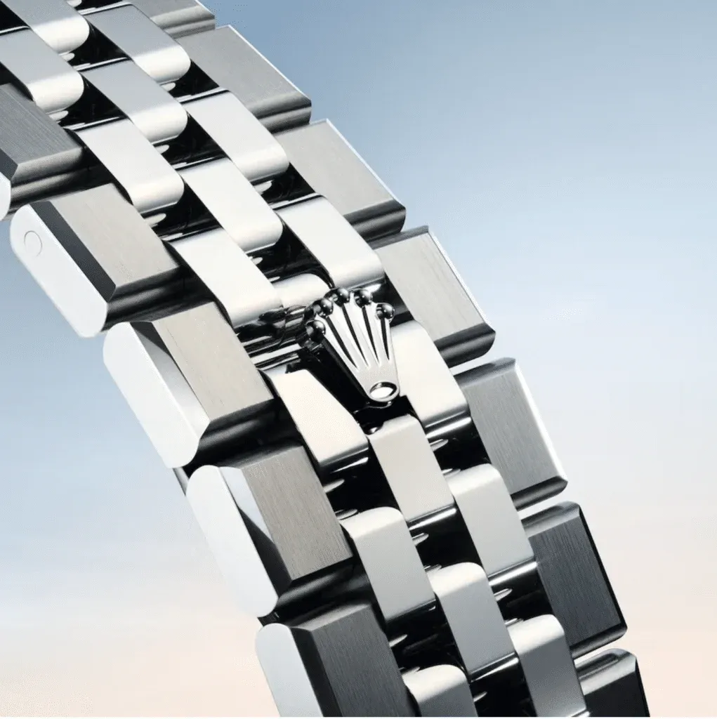 Close-up view of a metallic watch bracelet featuring a distinctive Rolex crown logo, set against a soft gradient background.