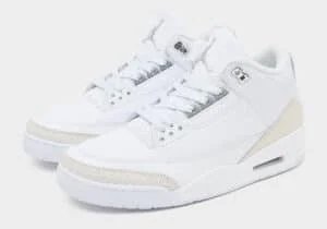 A pair of white sneakers featuring a sleek design with textured detailing, a perforated leather upper, and a visible air cushioning system in the sole.