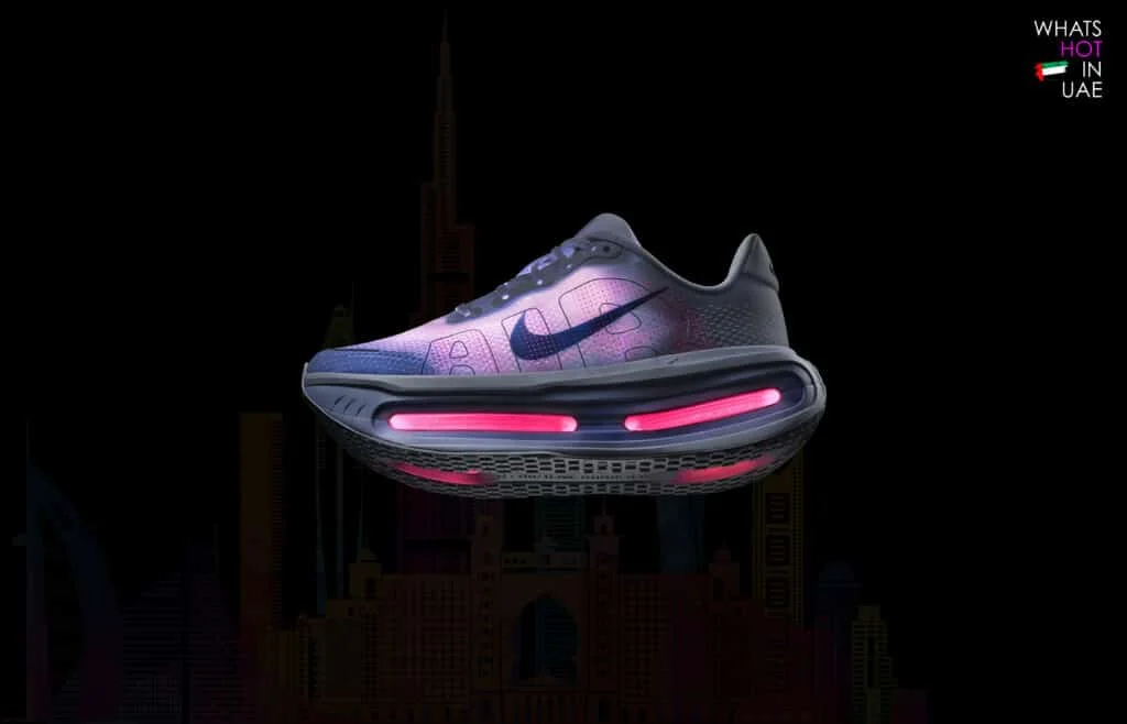 A stylish Nike sneaker displayed against a dark background, featuring a gradient color scheme of purple and black with illuminated pink accents in the sole.