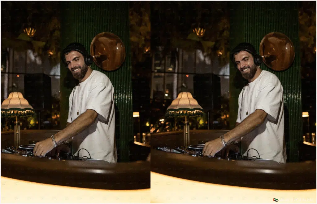 A DJ wearing headphones and a white T-shirt is mixing music on a DJ controller in a dimly lit, stylish venue with a vintage lamp in the background.
