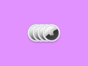 Four white Apple AirTags arranged in a row on a purple background.