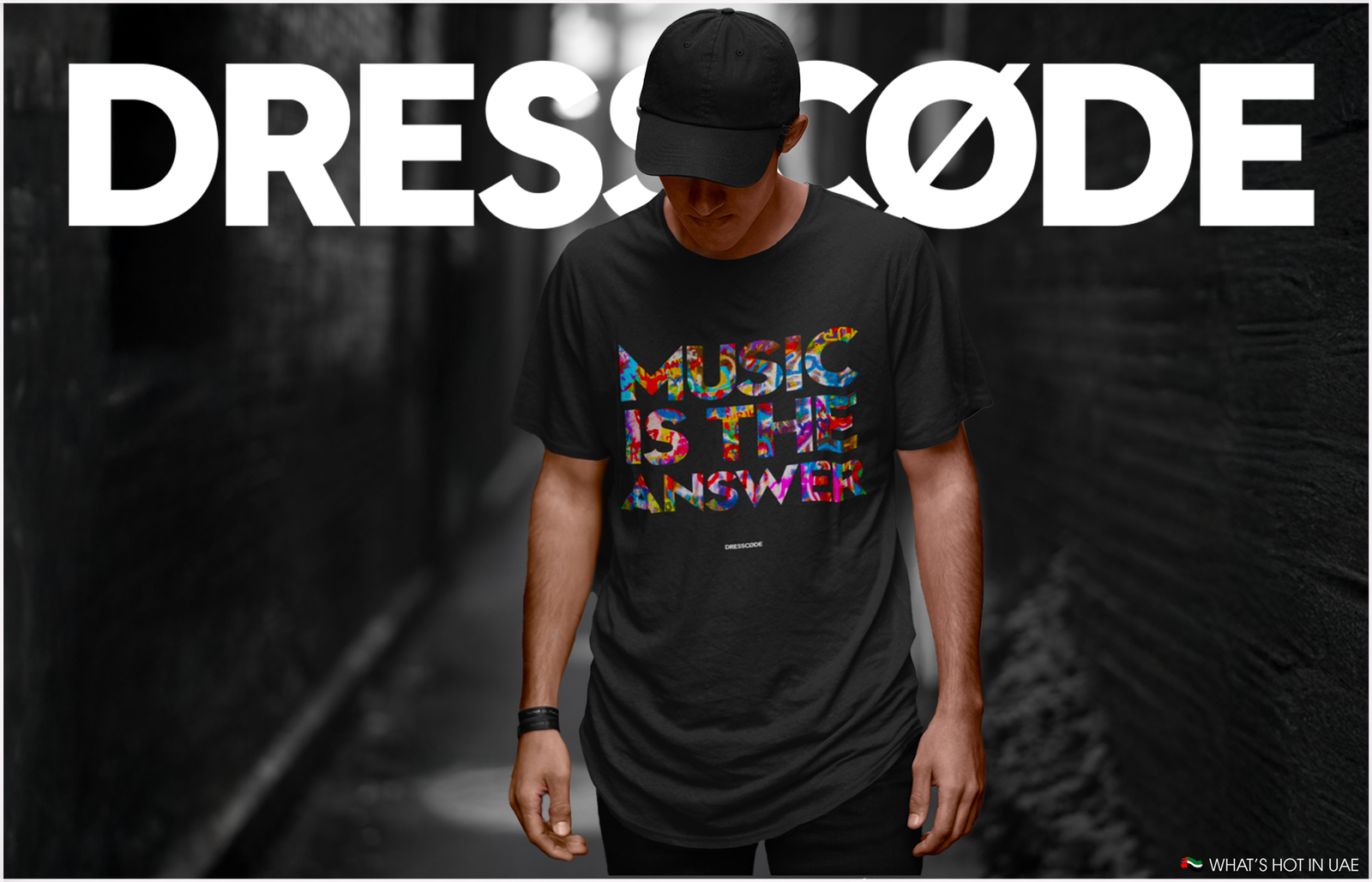 A person wearing a black t-shirt with colorful lettering that reads 'Music is the Answer' stands in a dark alley, with 'DRESSCØDE' written in large white letters above.