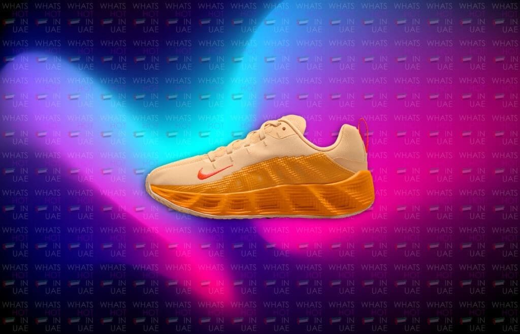 A stylish sneaker featuring a soft beige upper and a vibrant orange midsole, set against a colorful background with the text "WHATS HOT IN UAE" repeated in various colors.
