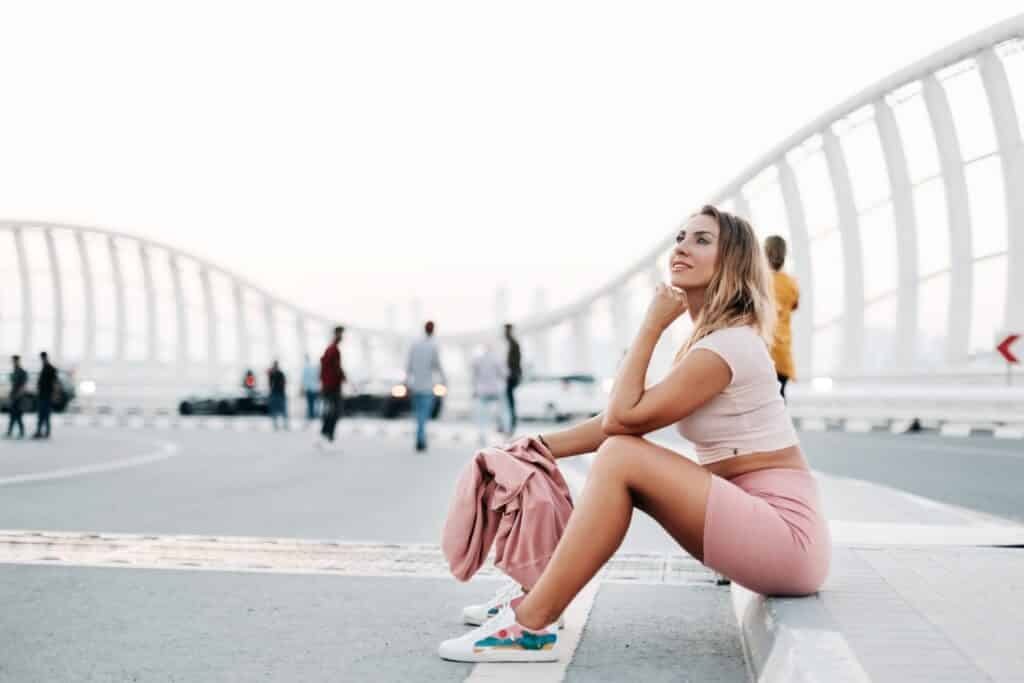 An attractive woman sits on the Meydan Bridge after a walk and smiles.