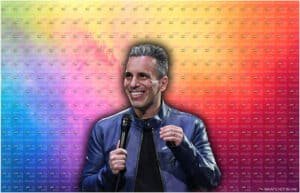 A person wearing a blue leather jacket holding a microphone against a colorful background with repeated text "What’s Hot in UAE."