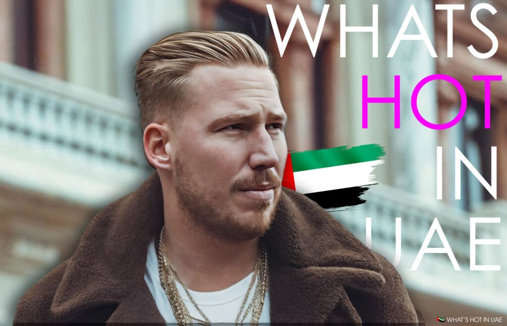 A person in a brown coat with layered necklaces, set against a background with the text 'WHAT'S HOT IN UAE' and an image of the UAE flag.