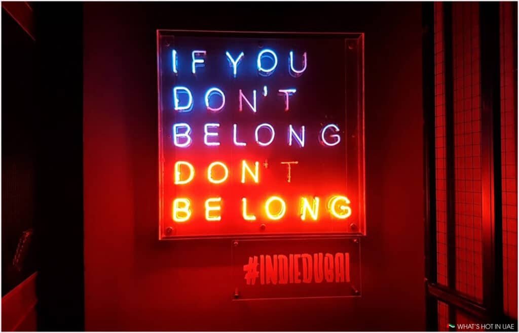 Neon sign with the words "IF YOU DON'T BELONG DON'T BE LONG" in blue and red lights, with a smaller sign reading "#INDIEDUBAI" beneath it, against a dark background. Bars we miss in DIFC