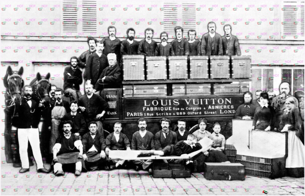 A group of men, women, and children posing with a horse-drawn cart loaded with luggage bearing the "Louis Vuitton" brand name and addresses in Paris and London. The people are dressed in period attire, and the setting is an outdoor urban environment.