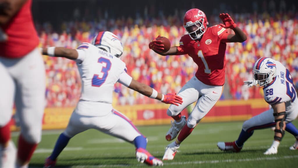 A digital image of a football game showing a player in a red uniform running with the ball, facing two defenders in white uniforms. The player dodges a tackle as the stadium crowd watches in the background.