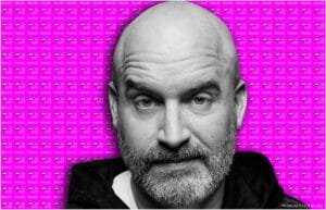 A black and white photo of Tom Segura with a beard against a vibrant pink background that repeats the phrase 'WHAT'S HOT IN UAE' alongside small UAE flags.