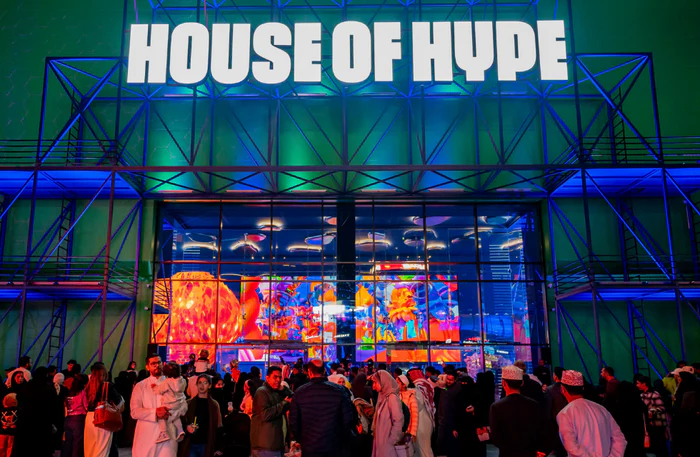 A large crowd gathers outside a building with a sign reading "House of Hype." The building is illuminated with colorful lighting and features large, vibrant digital displays inside. Family and Kids Activities in Dubai
