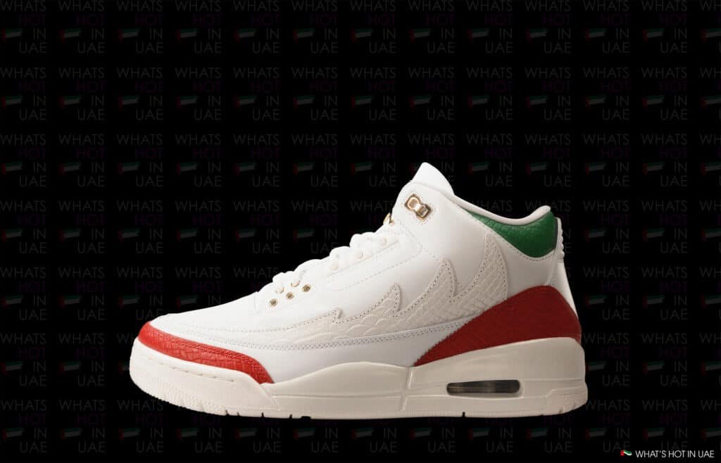 A white sneaker with red accents on the toe and heel, green detail near the ankle, and gold eyelets, set against a black background with the text "WHAT'S HOT IN UAE."