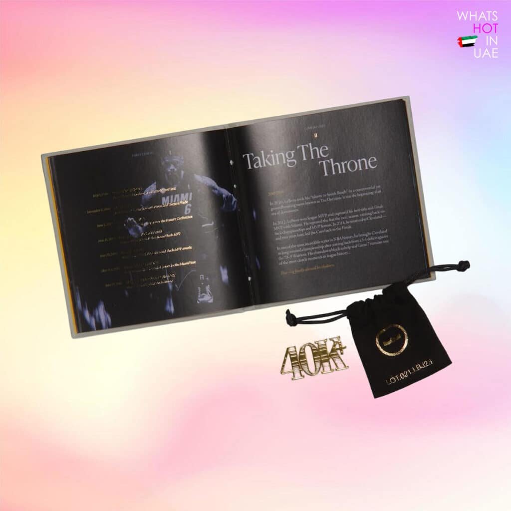An open book titled 'Taking The Throne' with text, accompanied by a small black drawstring pouch and a metal keychain, set against a gradient background with pink and yellow hues.