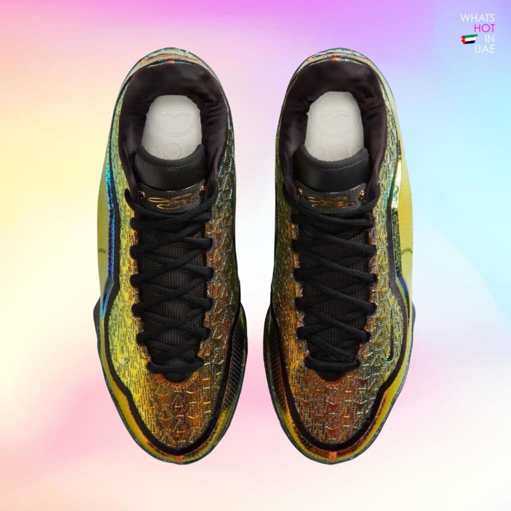 A pair of colorful high-top sneakers with intricate golden patterns and black laces, set against a gradient pastel background. Nike LeBron 23 “40K Gold”