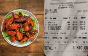A plate of glazed chicken wings on the left, garnished with lettuce and parsley, next to a restaurant receipt listing items like parotta, chicken 65, chicken lolipop, and biryani with a total amount of 810 INR.