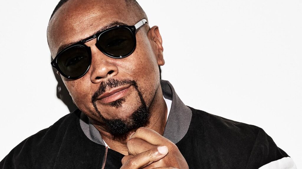 Timbaland in Dubai wearing sunglasses and a black jacket, posing against a plain white background.