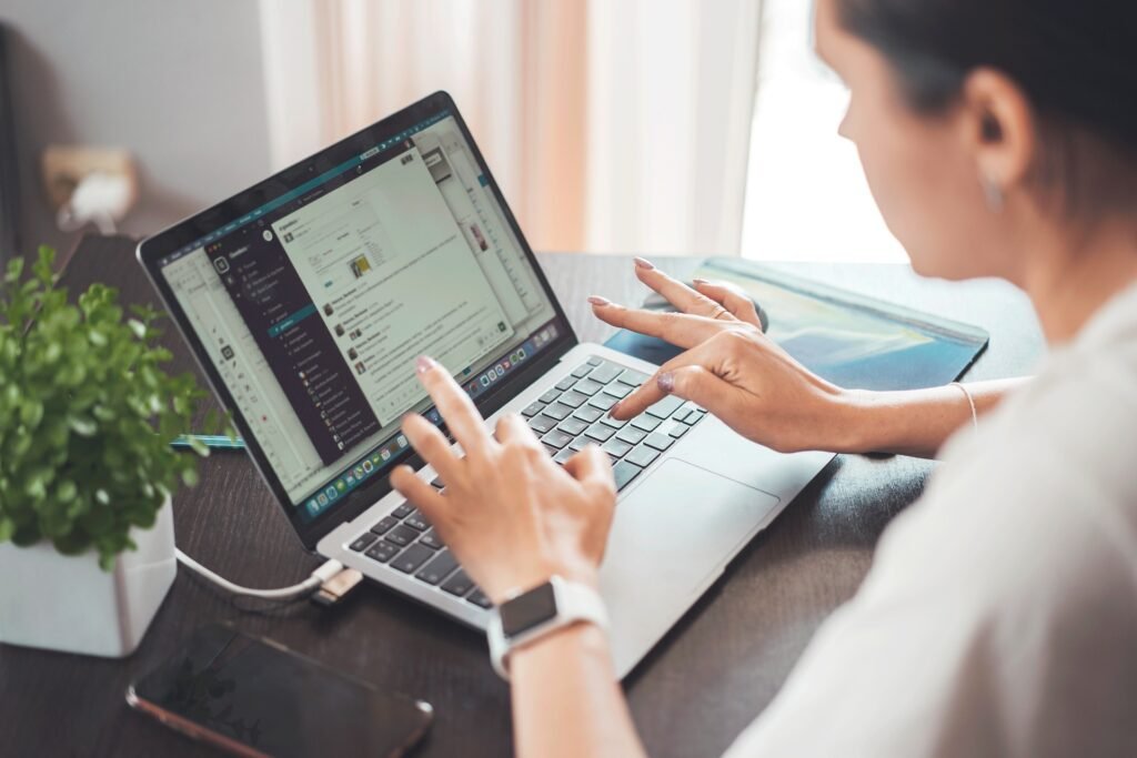 Person using a laptop at a desk with a communication app open on the screen, surrounded by a plant and smartphone. UAE internet users report slowdowns.