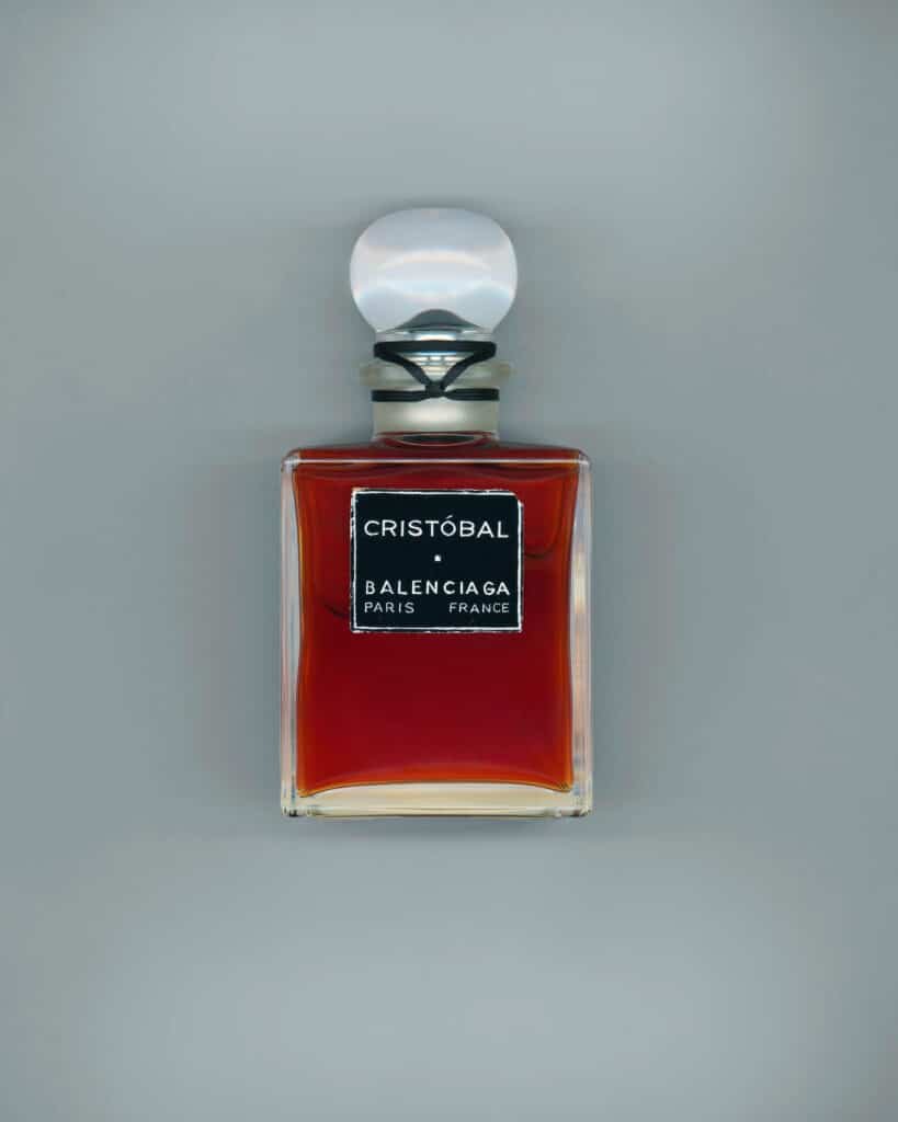 A bottle of Cristóbal Balenciaga Paris perfume with amber liquid, featuring a rounded glass stopper and a square black label on the front.