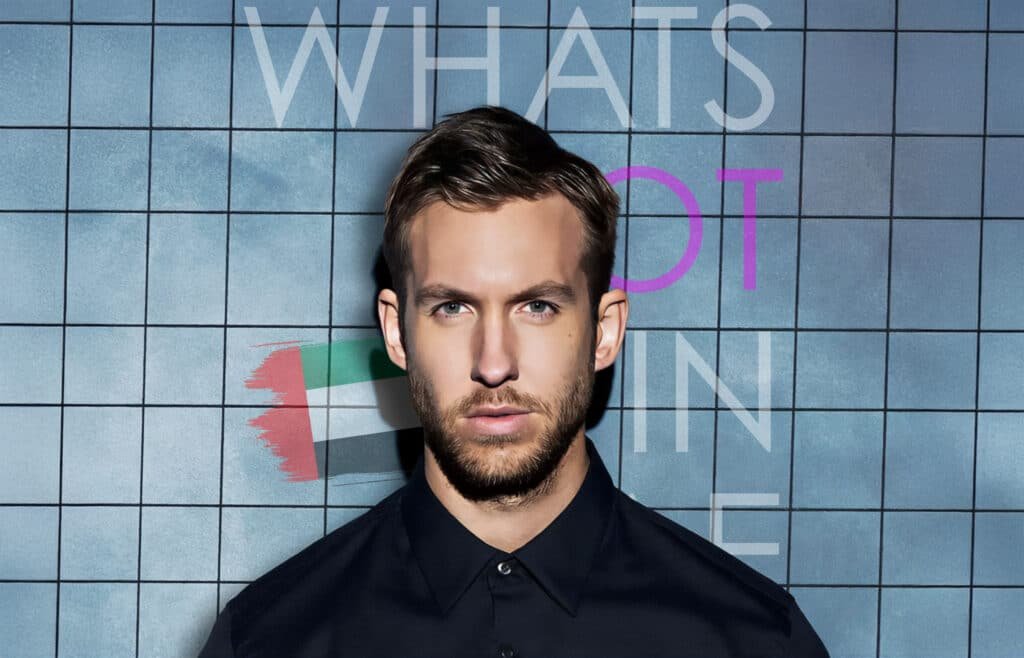 A man in a black shirt poses against a blue tiled background with the text "WHAT'S HOT IN" and a stylized image of the United Arab Emirates flag.