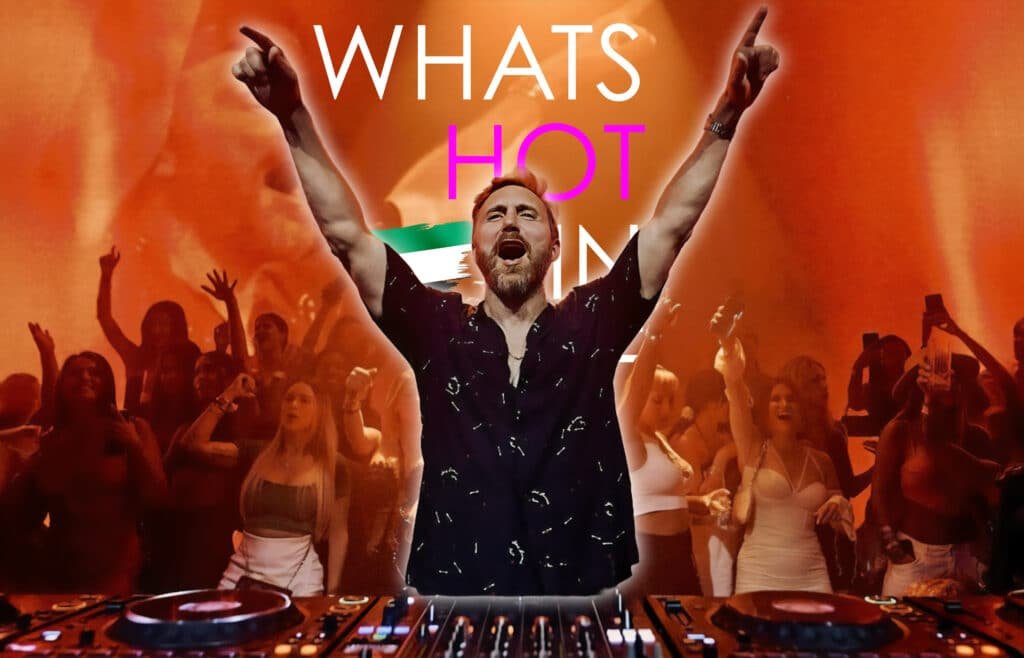 David Guetta with arms raised stands in front of a cheering crowd, with the words 'What’s Hot' in bold, colorful text against a vibrant, orange background.
