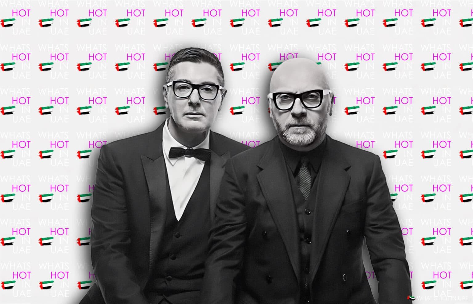 Two men in black suits and glasses stand in front of a backdrop with repeated text "WHAT'S HOT IN UAE" and images of the UAE flag.