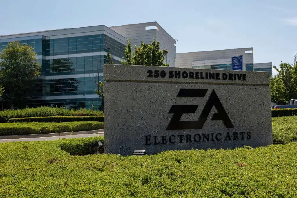 A sign for Electronic Arts at 250 Shoreline Drive, in front of a modern glass office building surrounded by greenery.