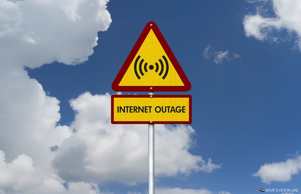 A triangular warning sign with an exclamation mark and Wi-Fi symbol above a rectangular sign reading "Internet Outage" against a backdrop of blue sky and clouds.