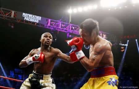 Two boxers engage in a match under bright arena lights, with one punching the other. A large sign above the ring displays their names, "Mayweather Pacquiao."