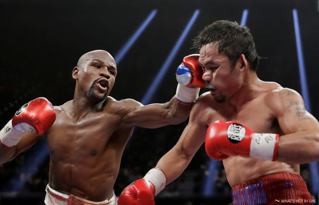 Pacquiao vs. Mayweather Rematch: Two boxers in a ring, with one delivering a punch to the other's face. Both are wearing red boxing gloves and have muscular builds. The boxer on the right has his eyes closed and appears to be recoiling from the impact, while the one on the left has a determined expression. The background is dark with bright arena lights visible.