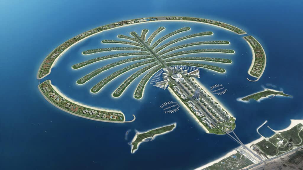Tourist Spots in Dubai: Aerial view of a large, man-made island in the shape of a palm tree, surrounded by blue ocean water, with several small islands and marine facilities nearby.