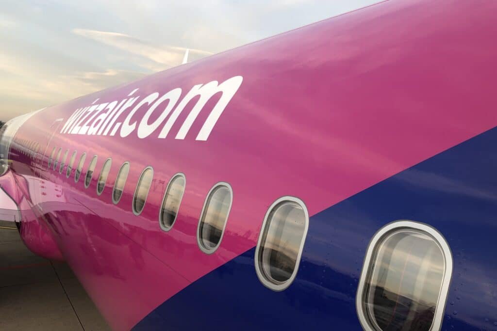 Close-up of a pink and purple airplane with the logo and windows visible, viewed from an angle on the tarmac.