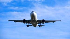 A commercial airplane flying overhead against a blue sky with scattered clouds.