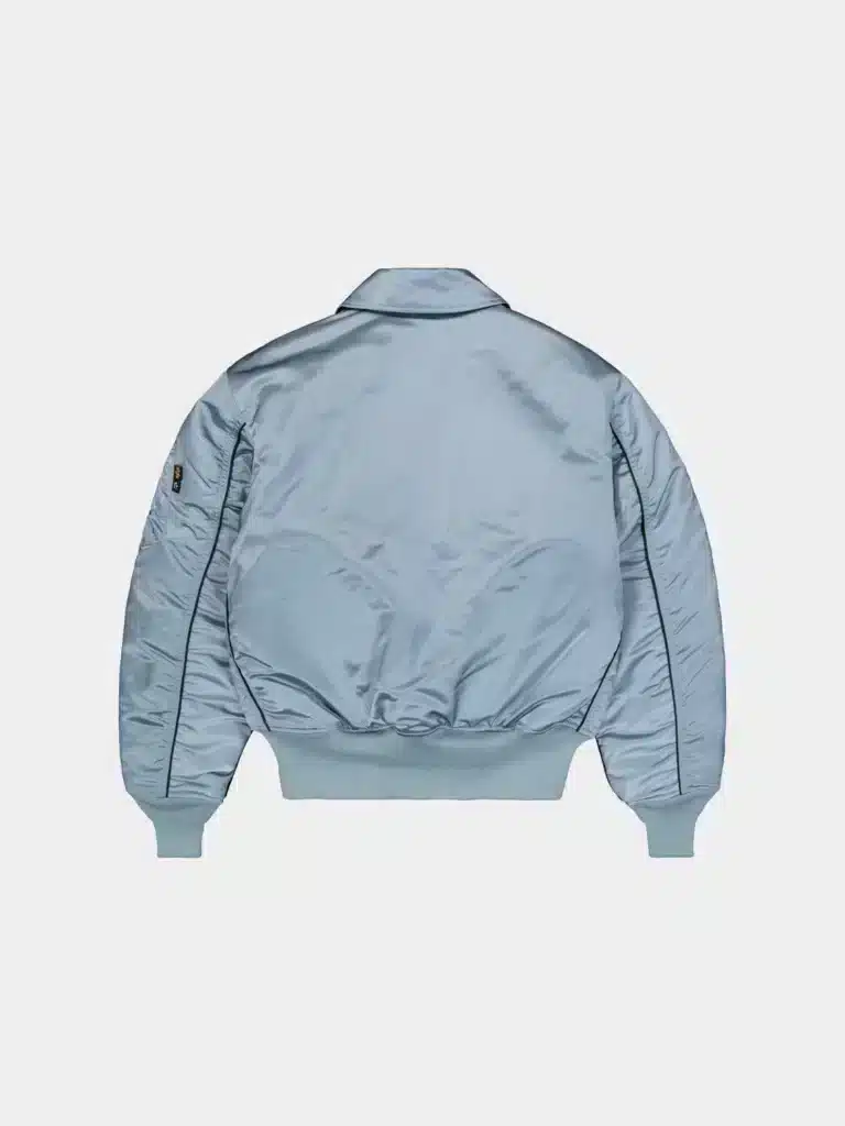 Back view of a light blue Alpha Industries x Peggy Gou bomber jacket with ribbed cuffs and hem, featuring a matte finish and a small logo patch on one sleeve.