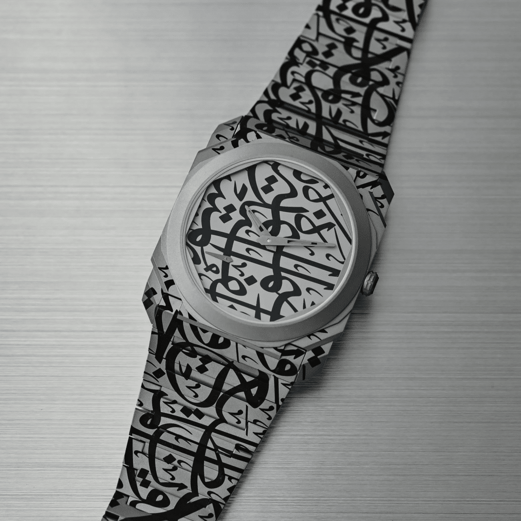 A Bvlgari Octo Finissimo wristwatch with an intricate geometric and calligraphic design on its face and stainless steel strap, placed on a brushed metal surface.