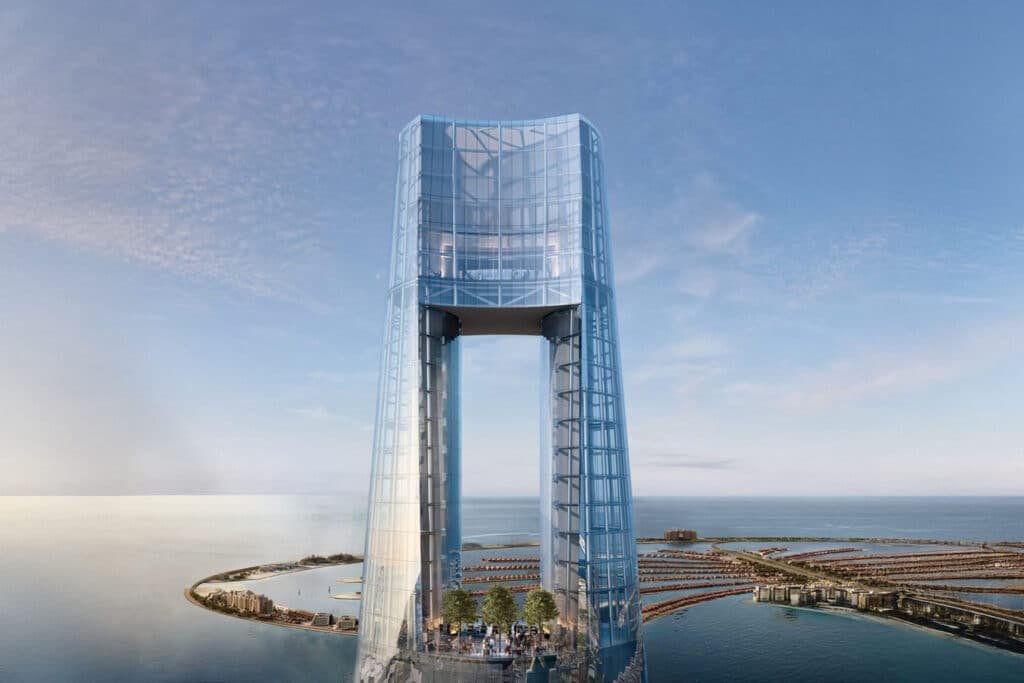 Ciel Dubai Marina: A modern architectural tower with a glass exterior set against a coastal landscape, featuring partially submerged structures resembling a circular pattern in the ocean.