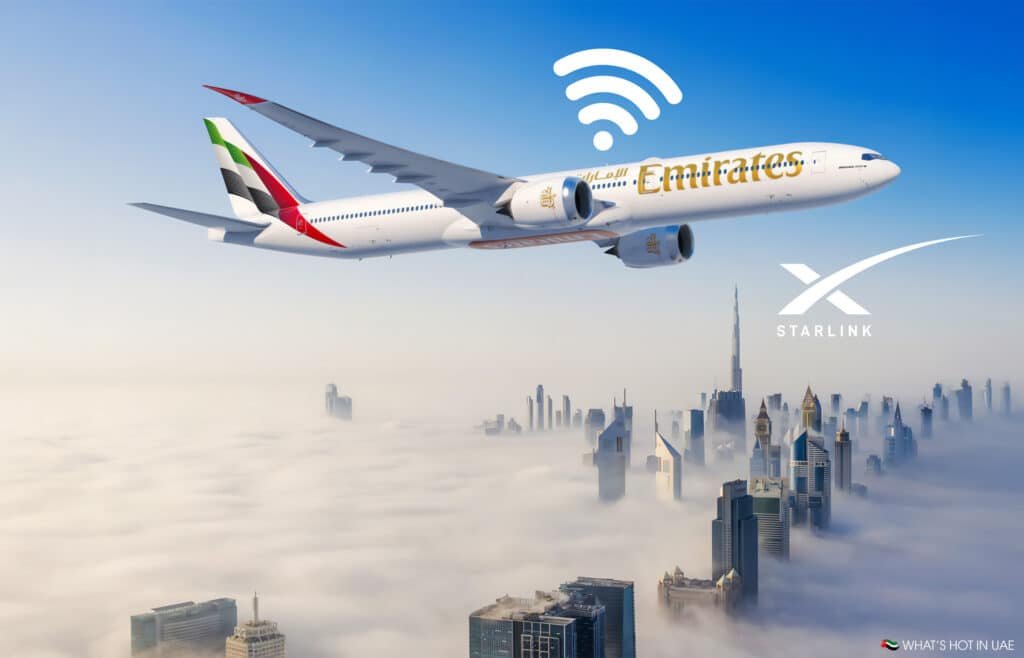 An Emirates airplane flying above a city obscured by clouds, with a WiFi symbol and Starlink logo, set against a backdrop of skyscrapers.