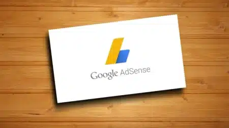 Google AdSense logo on a white card, set against a wooden background.