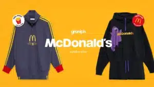 Two sweatshirts displayed against an orange background, part of a Graniph and McDonald's collaboration. The left sweatshirt is blue with yellow stripes, featuring the McDonald's logo and "dippin'" text. The right sweatshirt is black with a character graphic and "McDonald's" text. Two collection badges, "Feel-Good" and "Heritage," are visible.