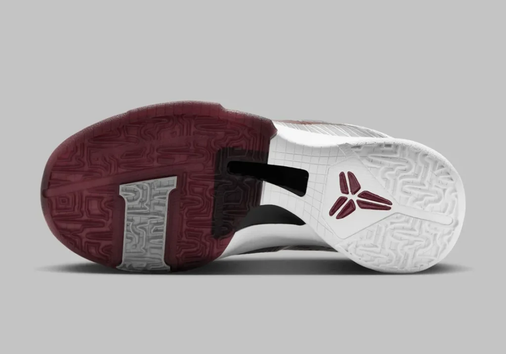 The outsole of a Nike Kobe 5 Protro 'Lower Merion Aces' sneaker featuring a dual-tone design with maroon and white sections, showcasing a textured pattern and a logo near the heel area.