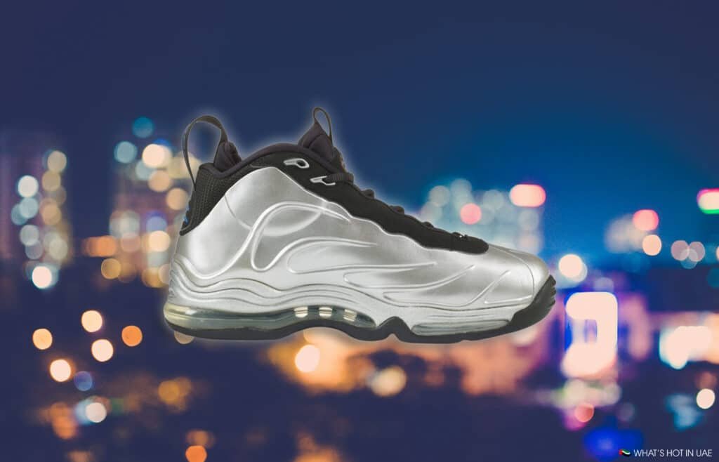 Nike Total Foamposite Max Retro (2026): A silver athletic shoe with black accents against a blurred city lights background.