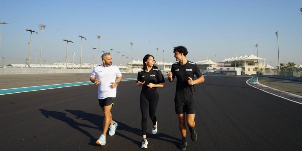 RunYAS 2026: Your Ultimate Guide to Abu Dhabi's New Running Festival at Yas Marina CircuitThree people jogging on a race track, with two men wearing sportswear and a woman in the middle, under a clear blue sky.
