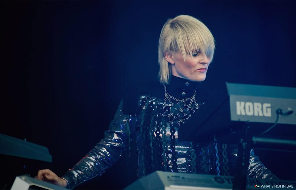 Sister Bliss with short blonde hair wearing a sequined outfit playing a Korg keyboard on stage at Synthony.