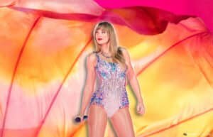 A person in a sparkly bodysuit holds a microphone against a vibrant, colorful background.