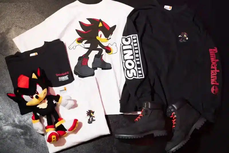 Assorted items featuring Shadow the Hedgehog, including two t-shirts with his image, a plush toy, and a pair of black boots with red accents and Timberland branding.