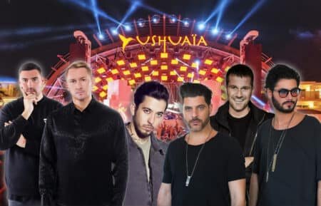 A group of six men standing in front of a stage with bright lights and the word 'Ushuaïa' displayed prominently, suggesting a music festival or concert venue.