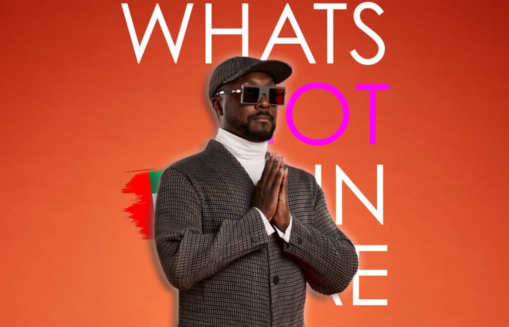 A person wearing a checkered jacket, cap, and large sunglasses stands against an orange background with the partial text "WHATS HOT IN" behind them.