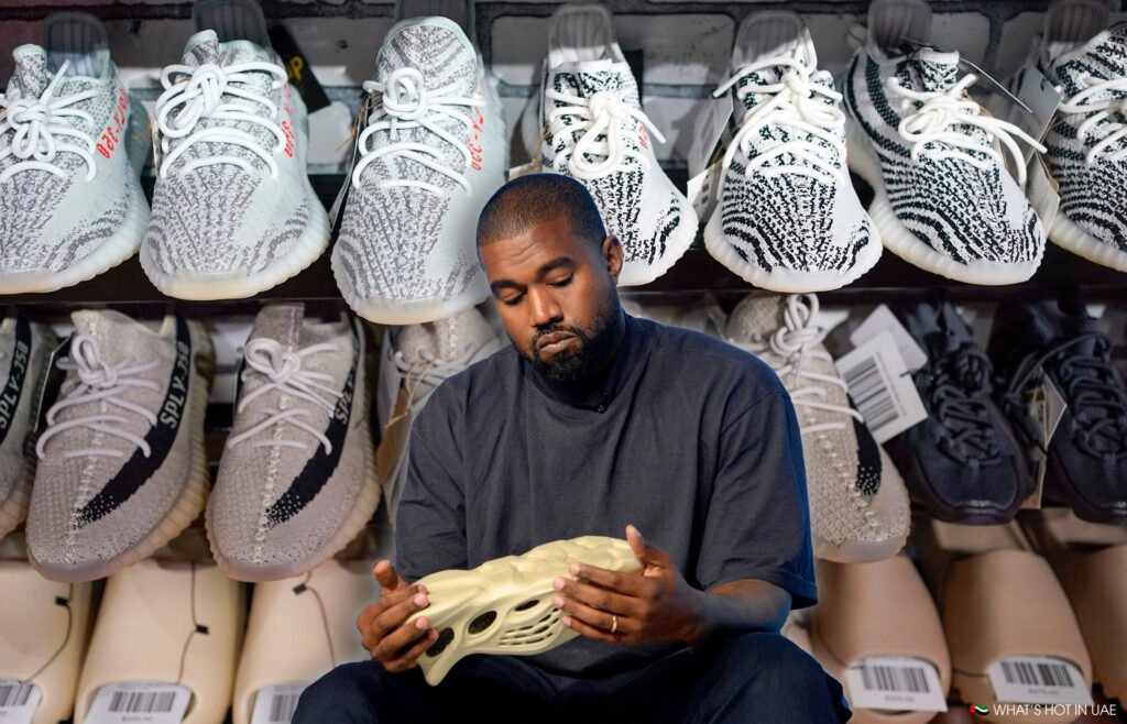 A person sitting and examining a sneaker, surrounded by shelves filled with various patterned sneakers.